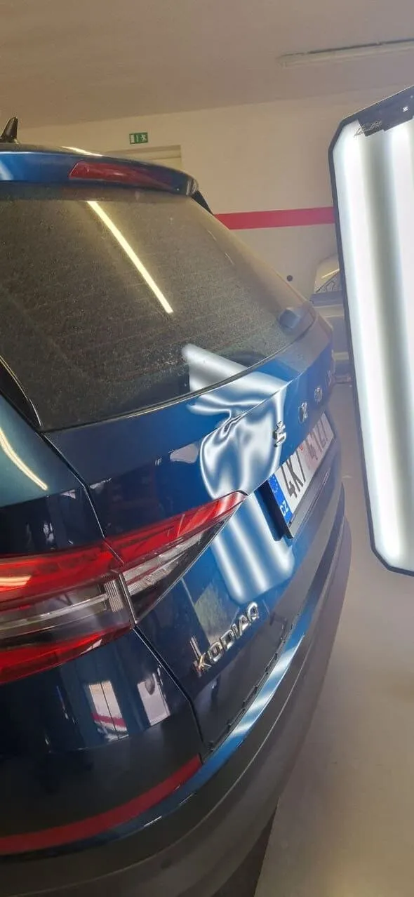 Вмятина на крышке багажника синего автомобиля Škoda Kodiaq после вандализма до ремонта